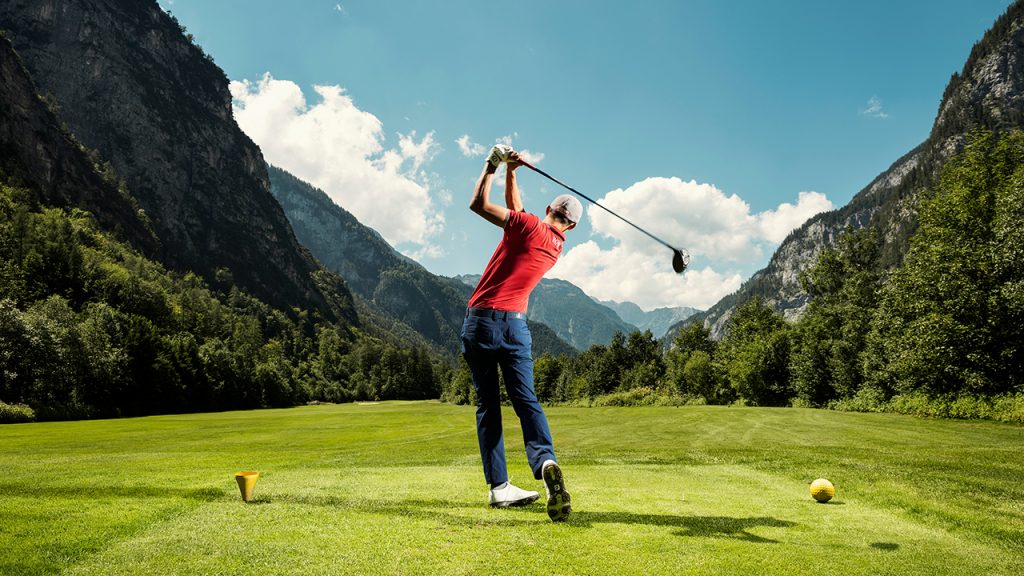 Ein Golfer nach dem Abschlag, ringsum Berge
